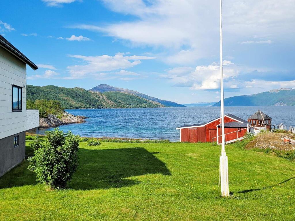 a house and a pole next to a body of water at 6 person holiday home in Sandhornøy in Røssnes