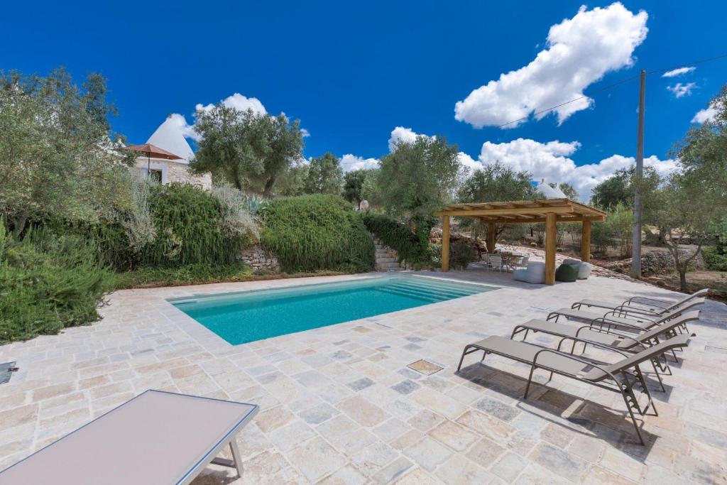 une piscine avec des chaises et un gazebo dans l'établissement Trullo Lui di Borgo Paoli by Perle di Puglia, à Ceglie Messapica