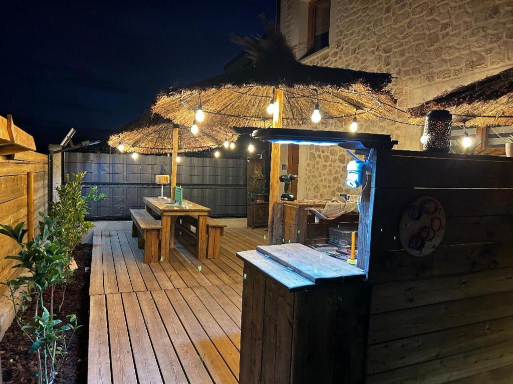 a patio with an umbrella and a table and benches at Les Chambres de Paulette à Theme LA JUNGLE ROOM in Sainte-Marie-la-Mer