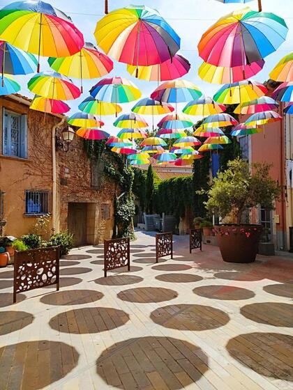 a bunch of umbrellas hanging over a courtyard at Les Chambres de Paulette à Theme LA JUNGLE ROOM in Sainte-Marie-la-Mer