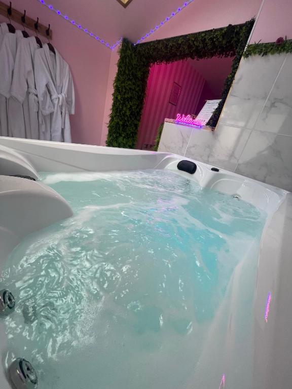 La salle de bains est pourvue d'une baignoire remplie d'eau bleue. dans l'établissement Maison Spacieuse Jacuzzi Wifi Netflix, à Quiévrechain