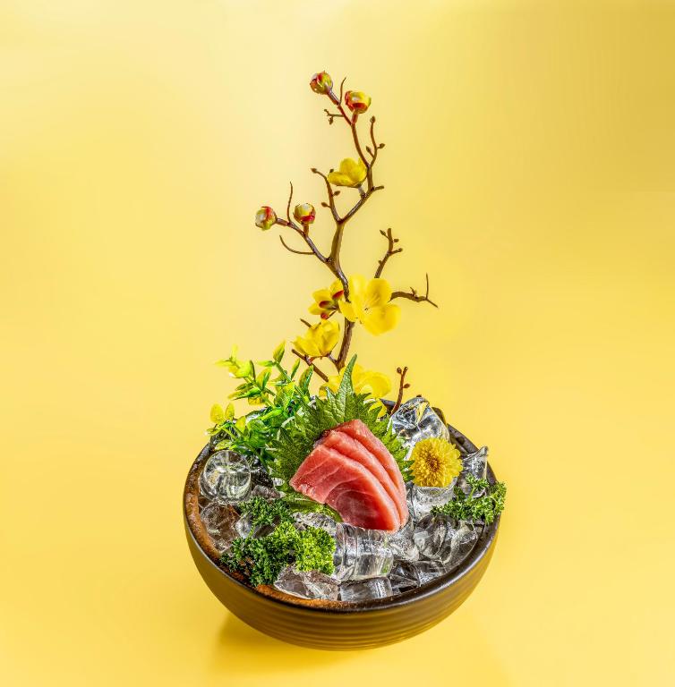 a vase filled with flowers and a piece of sushi at AG Hotel in Abu Dhabi