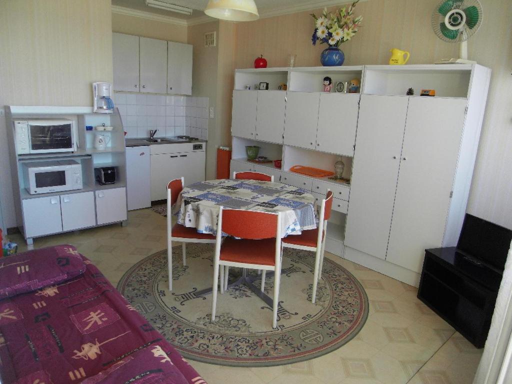 une cuisine avec une table, des chaises et des armoires blanches dans l'établissement Appartement vue mer, à Saint-Jean-de-Monts