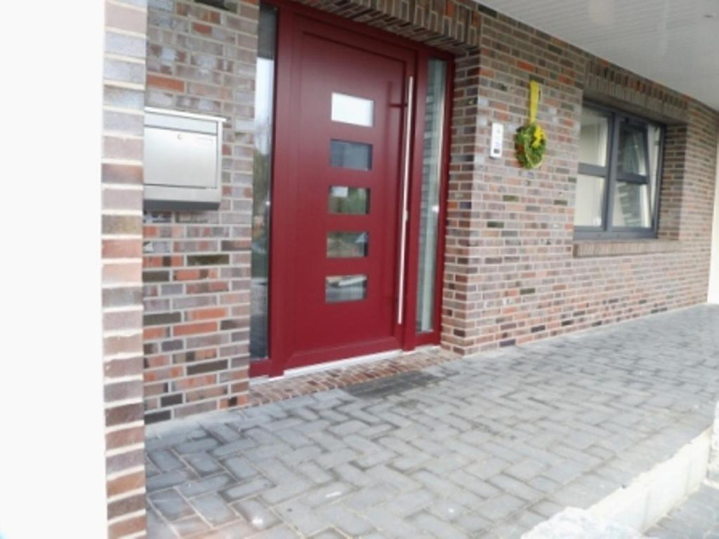 une porte rouge sur le côté d'un bâtiment en briques dans l'établissement Gästezimmer Haus Tulpenstraße, à Elsfleth