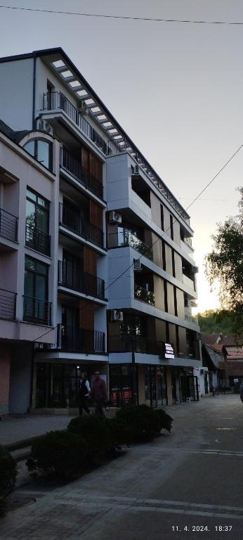 a large apartment building with people walking in front of it at CENTAR CEPERKOVIC in Vrnjačka Banja