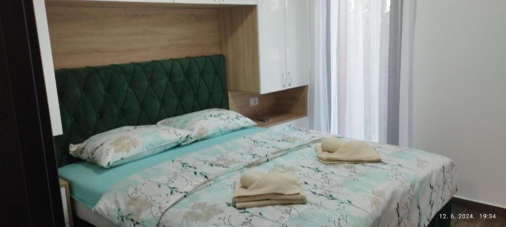 a bed with a green headboard and two towels on it at CENTAR CEPERKOVIC in Vrnjačka Banja