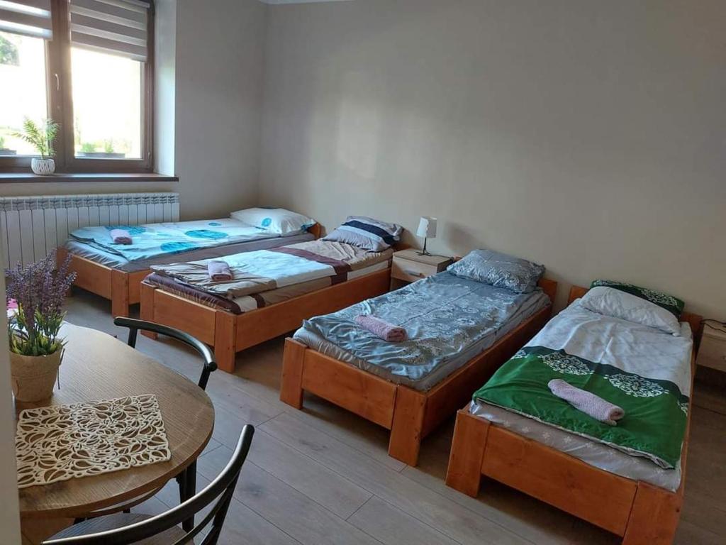 Habitación con 3 camas, mesa, mesa y sillas. en Lawendowy zakątek, en Graboszyce