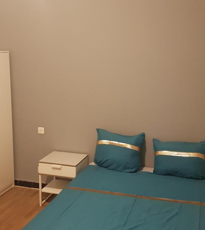 un lit avec des oreillers bleus et une table de chevet dans l'établissement Apprt'Nadia, à Avignon