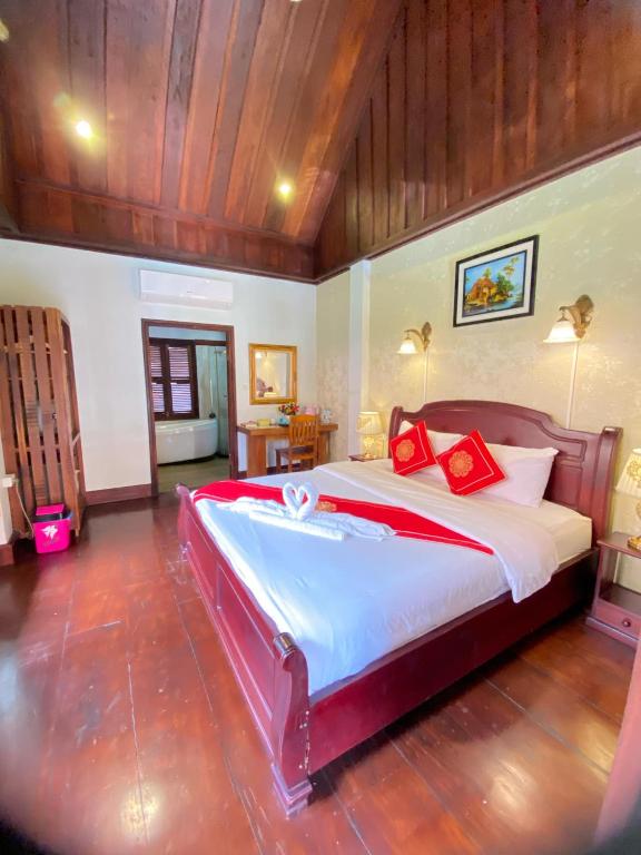 a large bedroom with a large bed with red pillows at Luangprabang Villa Kee Lee in Luang Prabang