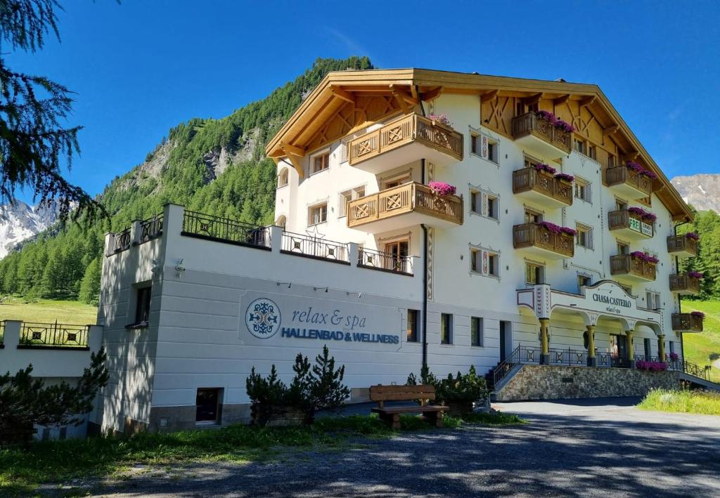 a large white building with balconies on a mountain at Chasa Castello relax & spa in Samnaun