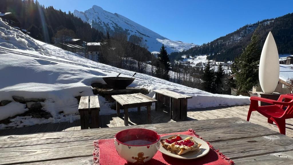 - une table avec un bol de nourriture au sommet d'une montagne enneigée dans l'établissement LA CLUSAZ avec TERRASSE, à La Clusaz