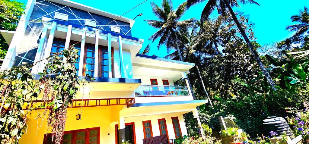 a yellow building with palm trees in front of it at Dean Dale Cottages in Thekkady