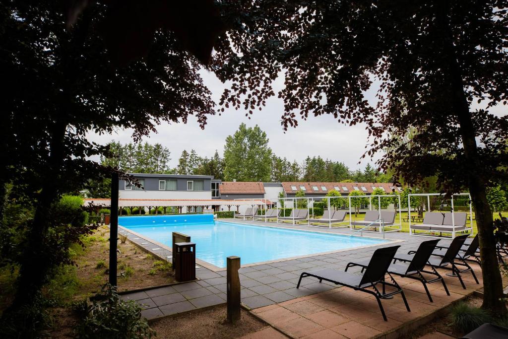 een zwembad met ligstoelen naast een gebouw bij Veluwe Hotel De Beyaerd in Hulshorst