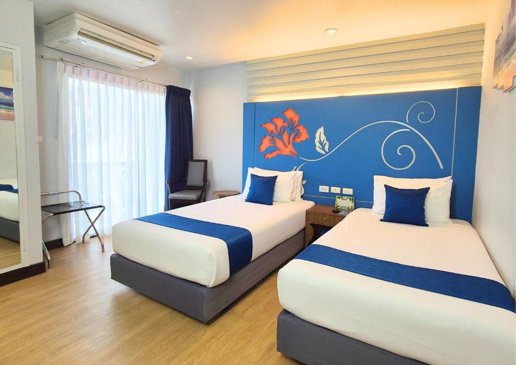 a hotel room with two beds and a blue wall at Days Inn by Wyndham Patong Beach in Patong Beach