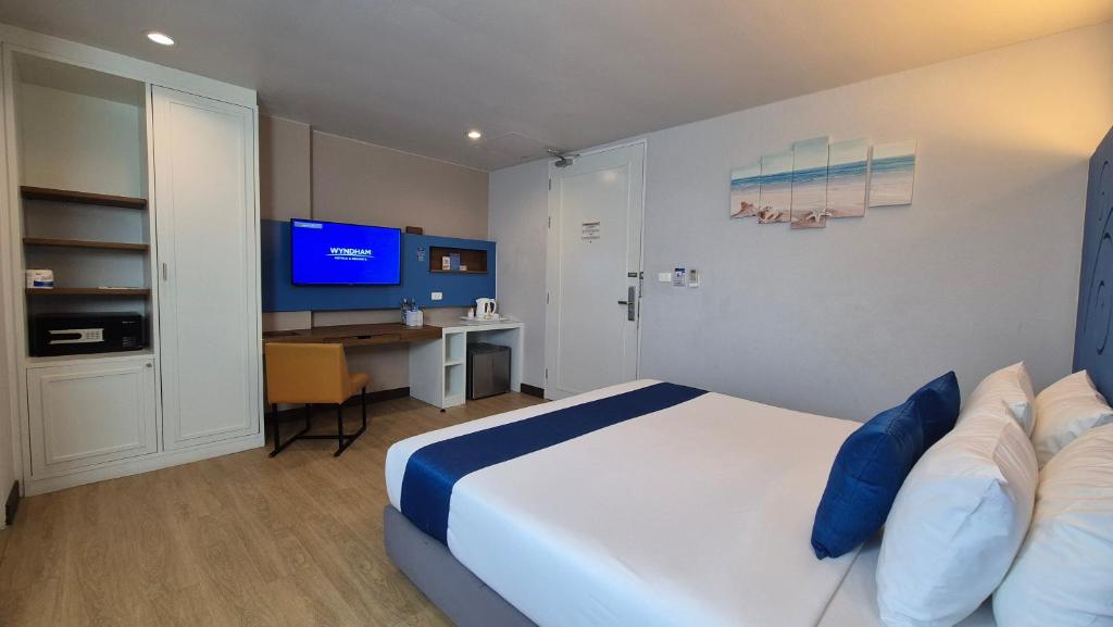a bedroom with a bed and a desk and a television at Days Inn by Wyndham Patong Beach in Patong Beach