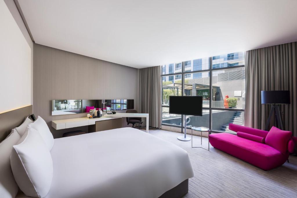 a hotel room with a white bed and a purple couch at InterContinental Dubai Marina by IHG in Dubai
