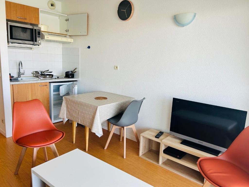 un petit salon avec une table et une télévision dans l'établissement L'Horizon - Parking - Piscine, à La Rochelle