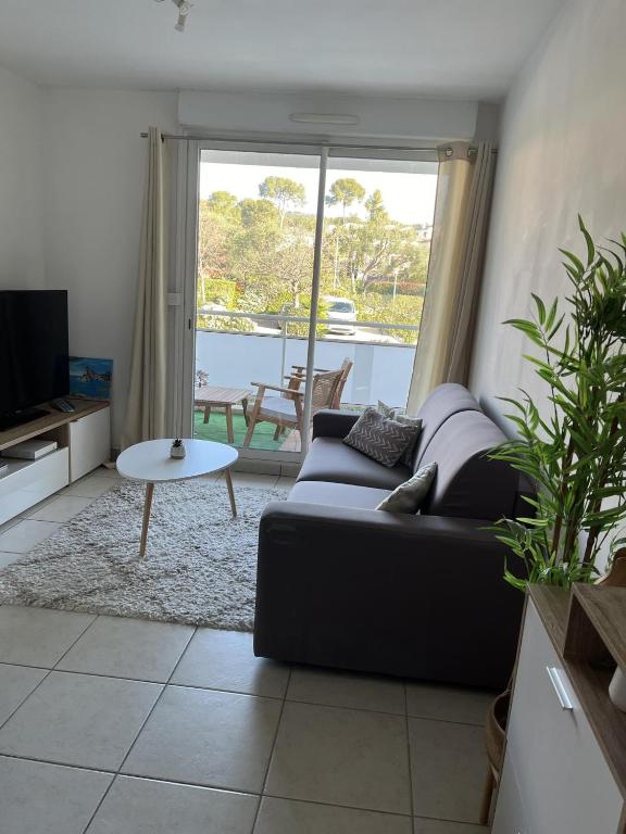 un salon avec un canapé et une table dans l'établissement Appartement lumineux climatisé avec terrasse, à La Ciotat