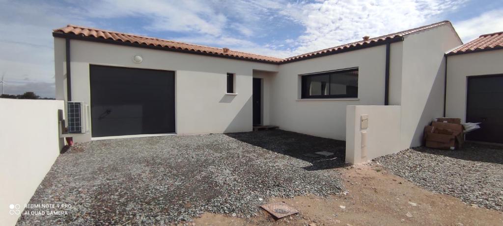 une maison avec deux portes de garage dans une cour dans l'établissement Belle maison neuve proche La Rochelle, à Ferrières