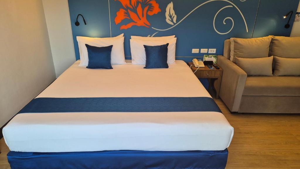 a large bed in a room with a couch at Days Inn by Wyndham Patong Beach in Patong Beach