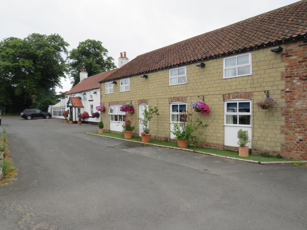 a house with potted plants on the side of a street at Ganton Greyhound Inn in Ganton