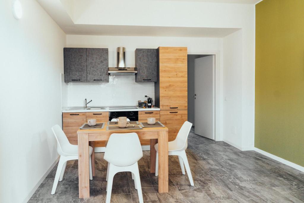 a kitchen with a wooden table and white chairs at Roberta House appartamenti vicino Humanitas e Forum Assago in Rozzano