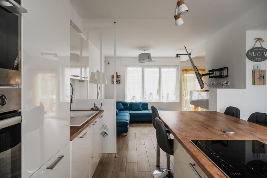 a kitchen with white cabinets and a blue couch at Maison des Clos Biais in Dinard