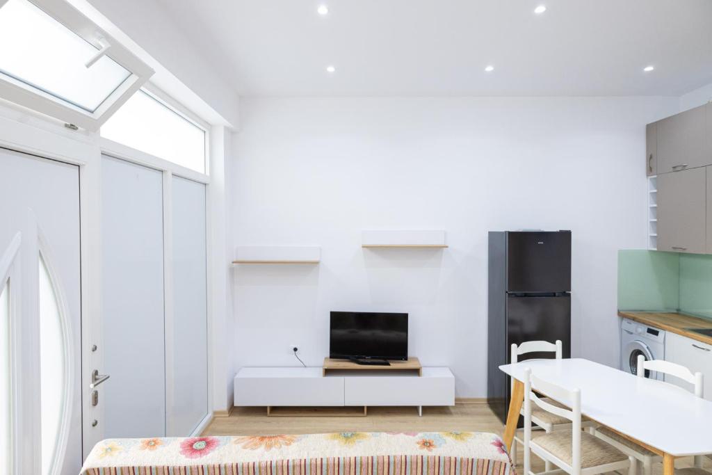 a white living room with a tv and a table at Lungomare luxury apartament in Vlorë