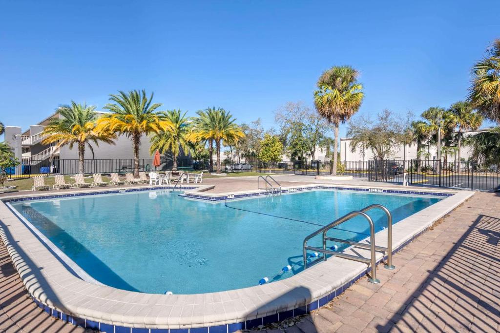 a large swimming pool with trees and palm trees at Suburban Studios International Drive in Orlando