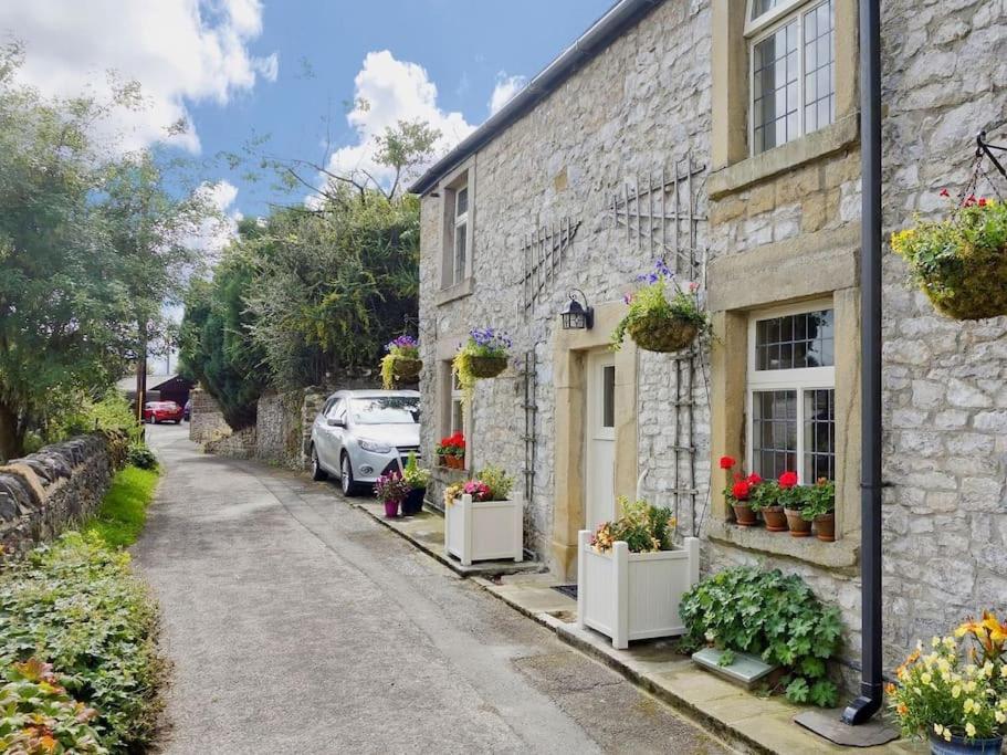a stone house with potted plants on a street at Peak District Luxury cottage, sleeps 8 plus pets in Tideswell