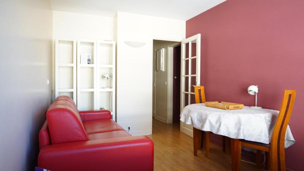 un salon avec une chaise rouge et une table dans l'établissement Rue de Longchamp - Paris 16, à Paris