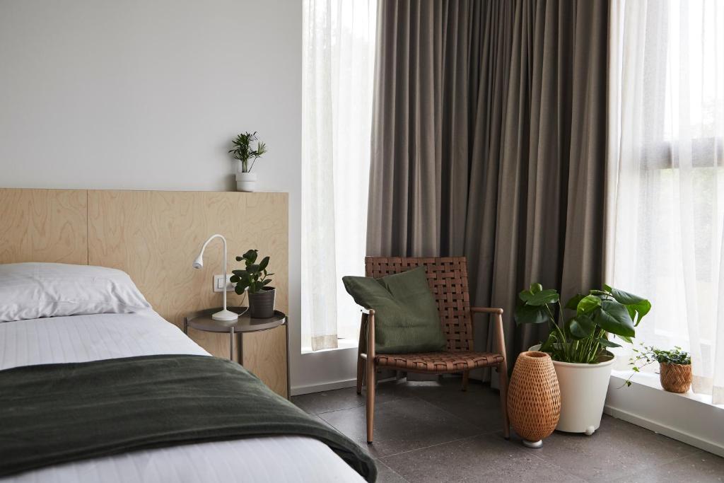 a bedroom with a bed and a chair and windows at Het Kasterhuis - Gastenverblijf in Wetteren