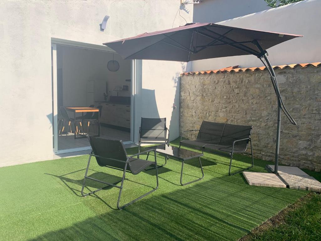 d'une terrasse avec des chaises et un parasol sur la pelouse. dans l'établissement VIDAGO maison neuve tout confort avec terrasse privée, à Nieul-sur-Mer