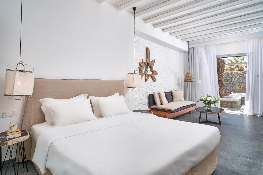 a white bedroom with a large bed and a living room at Hippie Chic Hotel in Agios Ioannis Mykonos