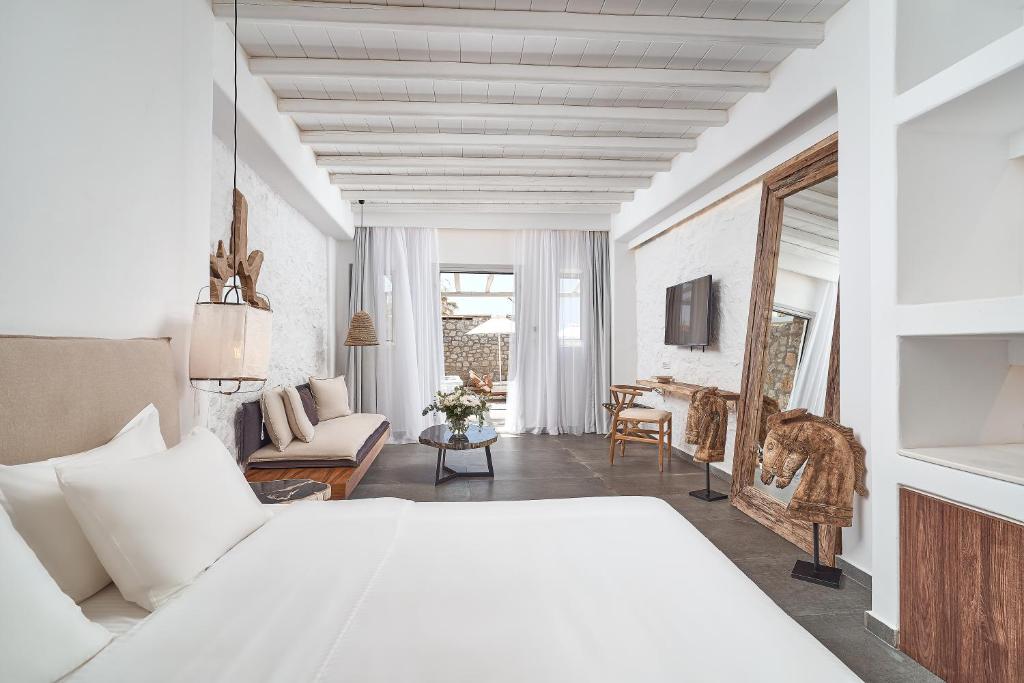 a bedroom with a white bed and a living room at Hippie Chic Hotel in Agios Ioannis Mykonos