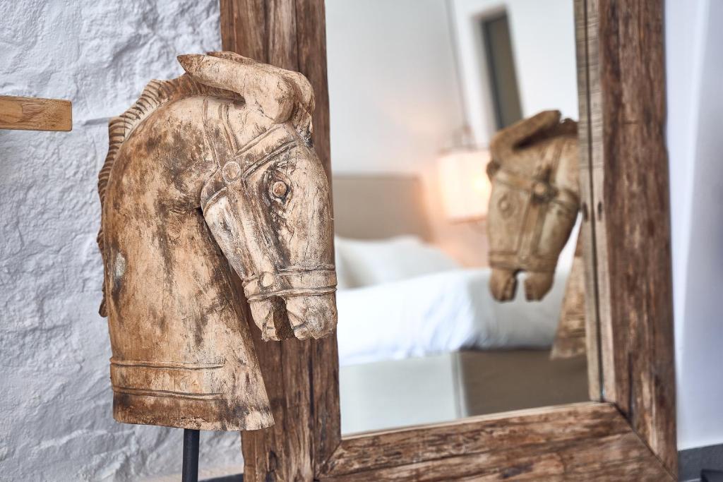a mirror on a wall with a statue of a horse at Hippie Chic Hotel in Agios Ioannis Mykonos
