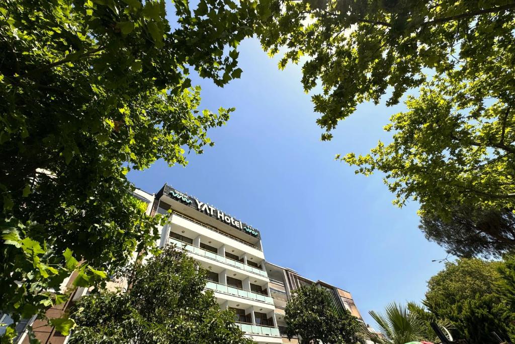 Un edificio blanco con árboles delante. en Tekirdağ Yat Hotel, en Tekirdağ