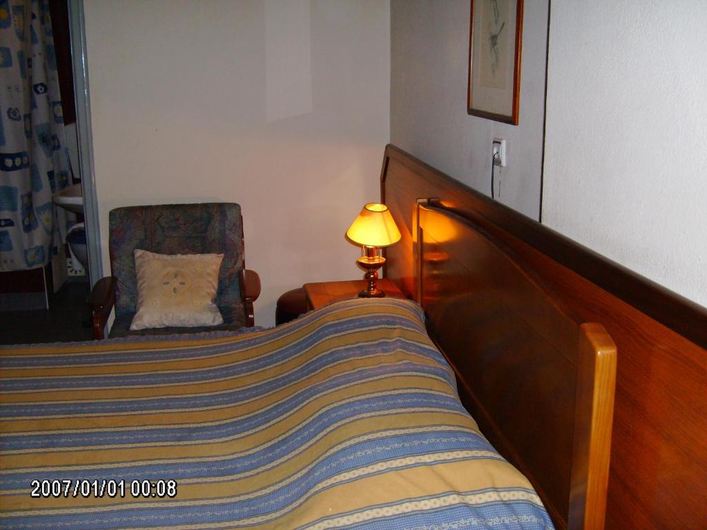 een slaapkamer met een bed, een lamp en een stoel bij Olhos Pretos in Caldas da Rainha