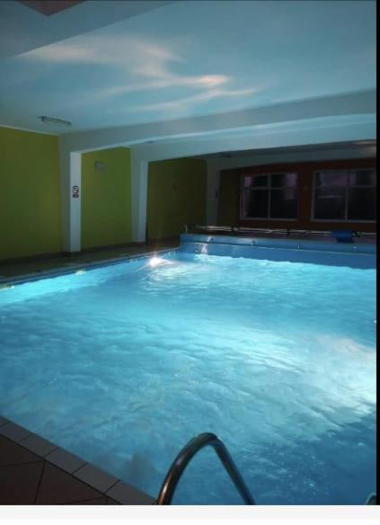 a large swimming pool with blue water in a room at Pokoje Gościnne u MARCINA- sala zabaw, basen, melex, rowery, grill in Ostrowo