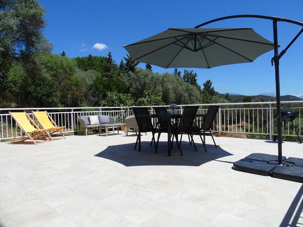 une table et des chaises avec un parasol sur une terrasse dans l'établissement Charmant rez de villa, et sa terrasse à Ajaccio, à Ajaccio