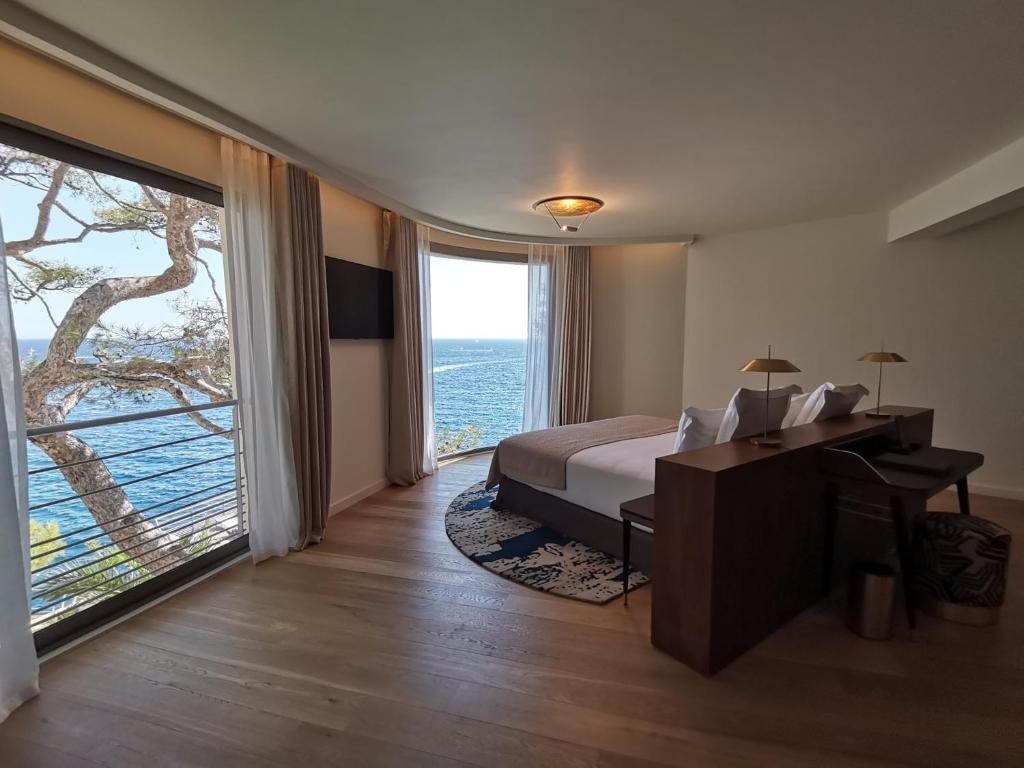 a hotel room with a bed and a large window at Hôtel Les Roches Blanches Cassis in Cassis