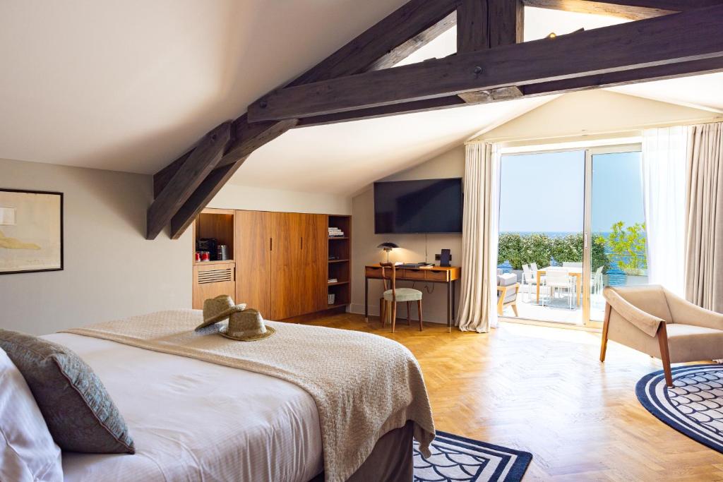 a bedroom with a large bed and a large window at Hôtel Les Roches Blanches Cassis in Cassis