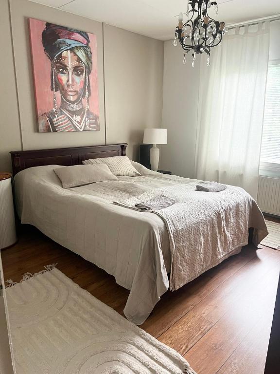 een slaapkamer met een bed met een schilderij aan de muur bij Kaksio paritalossa in Mikkeli