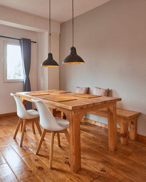 a wooden dining table with white chairs and two lights at Ananya Apartments Phase 1 in Kathmandu