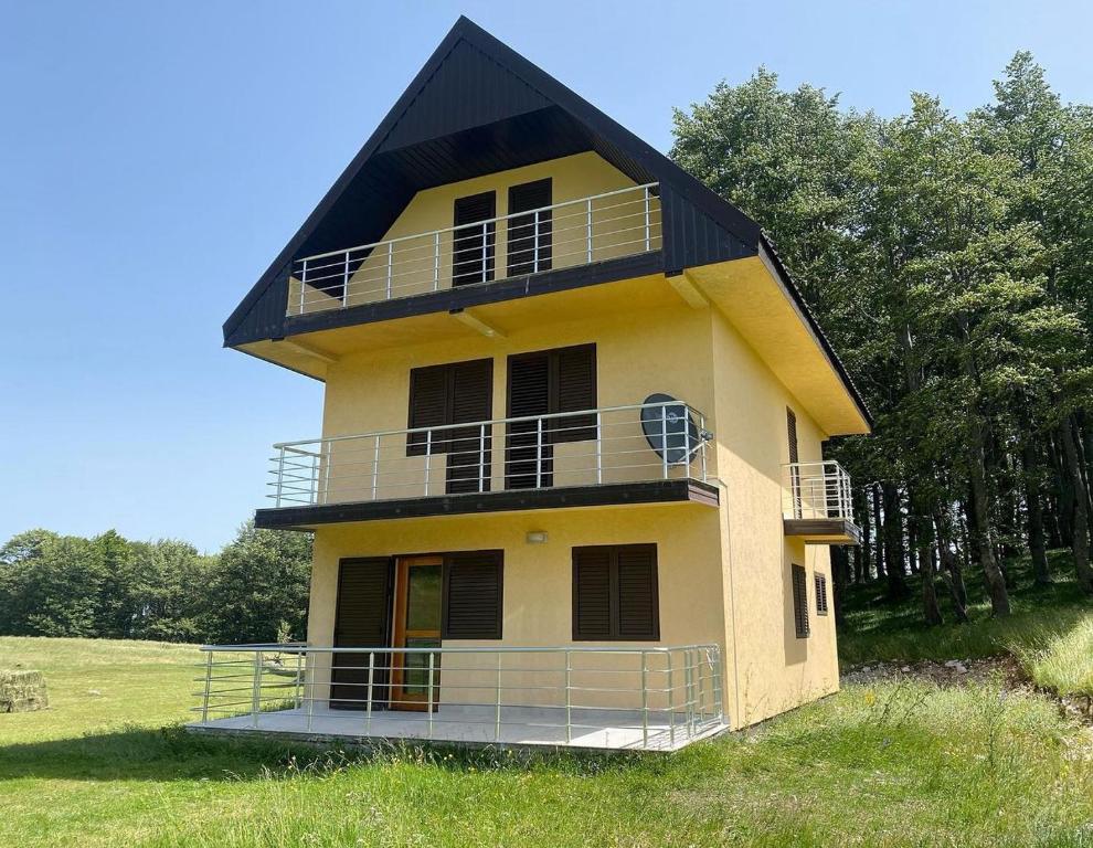a large yellow house with a black roof at Family house, Savin kuk in Žabljak