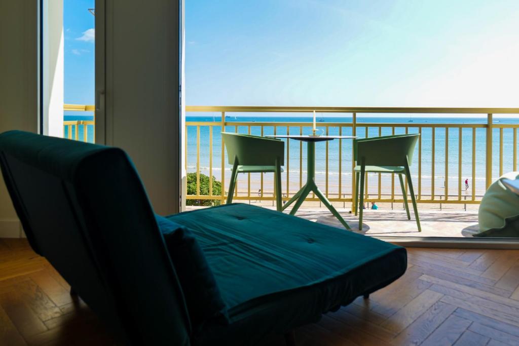 Cette chambre dispose d'un canapé et d'un balcon avec une table et des chaises. dans l'établissement Spacieux appartement avec vue magnifique sur la baie des Sables d'Olonne - 8 personnes, à Les Sables-dʼOlonne