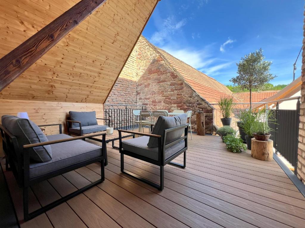 une terrasse en bois avec des chaises et une table dans l'établissement Maison 3 chambres et terrasse idéale couple d'amis, à Blaesheim
