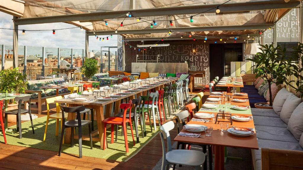 un restaurant avec de longues tables et des chaises sur un toit dans l'établissement Mama Shelter Bordeaux Centre, à Bordeaux