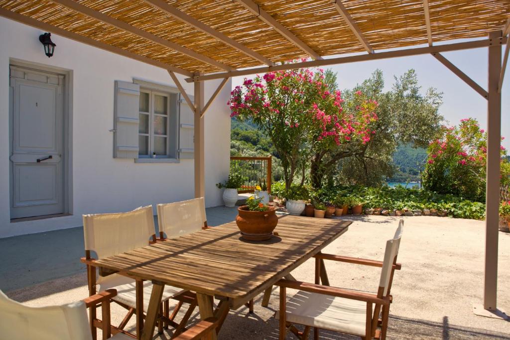 a wooden table and chairs under a wooden pergola at Skalopati Studios & Villa in Panormos Skopelos