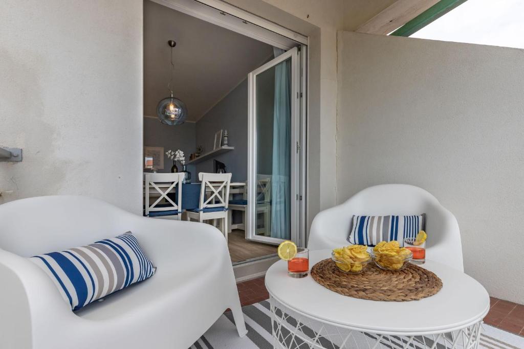 a living room with two white chairs and a table at Conero Suite in Marcelli